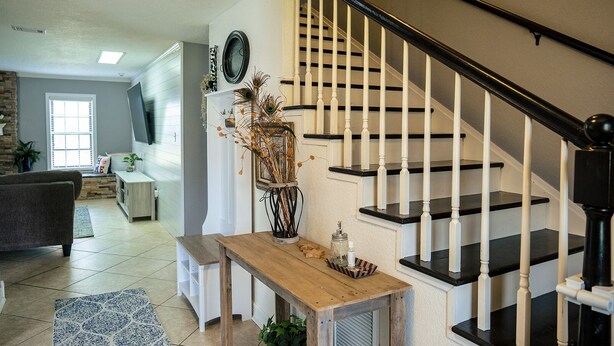 A spacious living room with a staircase, a dining area, and a kitchen visible in the background. - Luxe 5BR Family Retreat, Minutes From TAMU (College Station)
