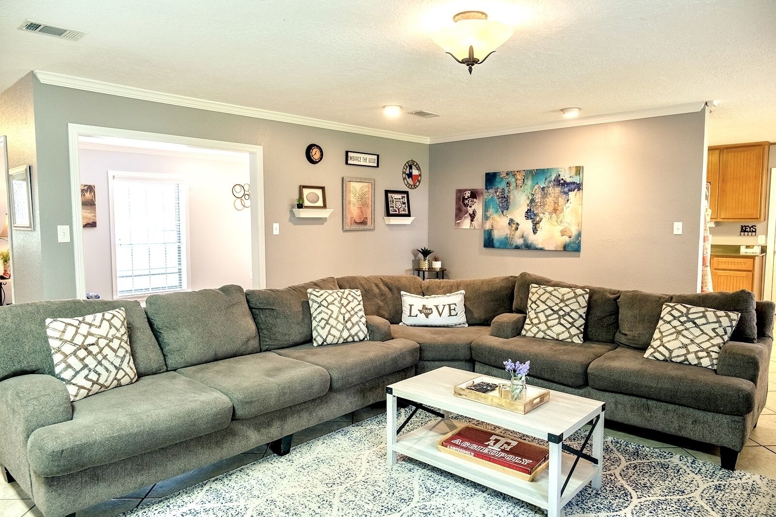 A living room with a sectional sofa, a coffee table, and various wall decorations including a clock and framed pictures.