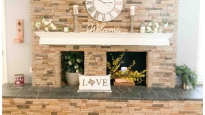 A fireplace with a stone facade, a large clock, and a welcome sign. - Luxe 5BR Family Retreat, Minutes From TAMU (College Station)