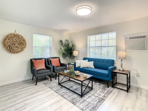 A living room with a blue sofa, two armchairs, a coffee table, and a large plant.