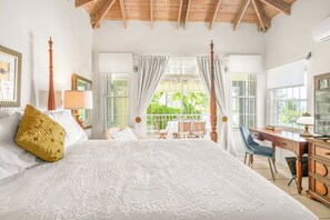 Un dormitorio con una cama grande, un escritorio y vistas a zonas verdes.