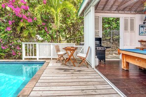 Une terrasse en bois avec une piscine, du mobilier d’extérieur et un barbecue.