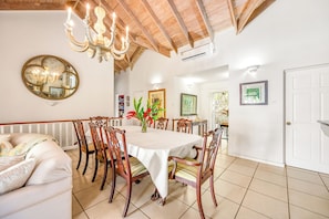 A dining area with a round table, chairs, a chandelier, and a mirror on the wall.