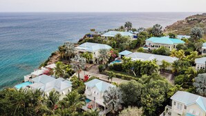 A coastal residential area with houses having blue roofs, surrounded by lush greenery and a view of the sea. - 4 Bedroom Villa in Calypso Bay Resorts with Fabulous Ocean View and Private Pool (Frigate Bay)