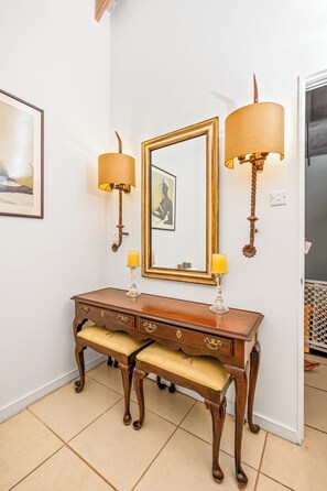 A wooden console table with two wall-mounted lamps and a mirror above it.
