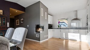 A modern kitchen with white cabinets, a built-in oven, and a window overlooking a garden.