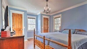 Une chambre à coucher avec un lit en bois, un bureau avec un téléphone et deux portes.