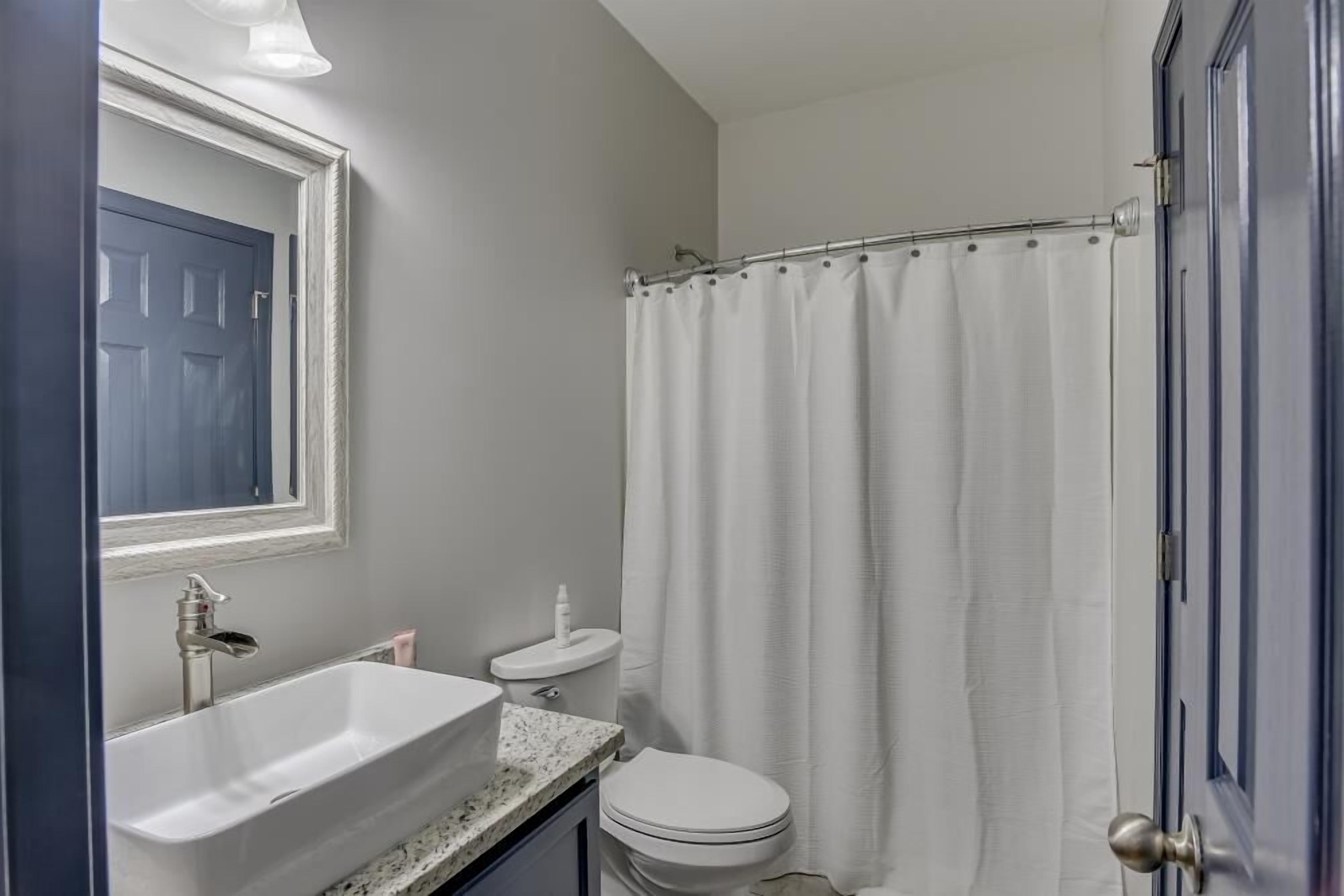 Une salle de bain avec un lavabo blanc, des toilettes et un rideau de douche.