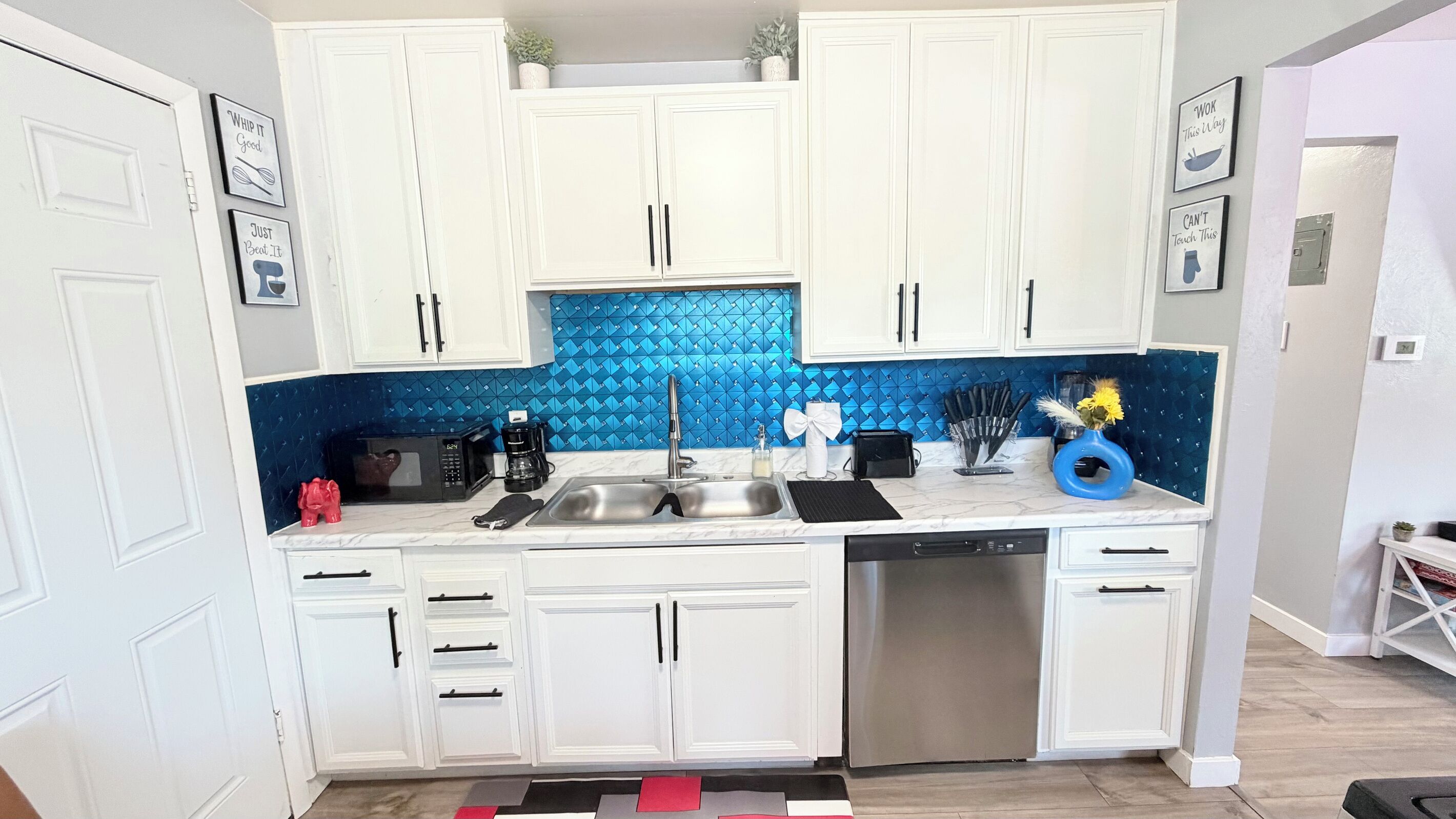 A modern kitchen with white cabinets, a blue backsplash, and stainless steel appliances.