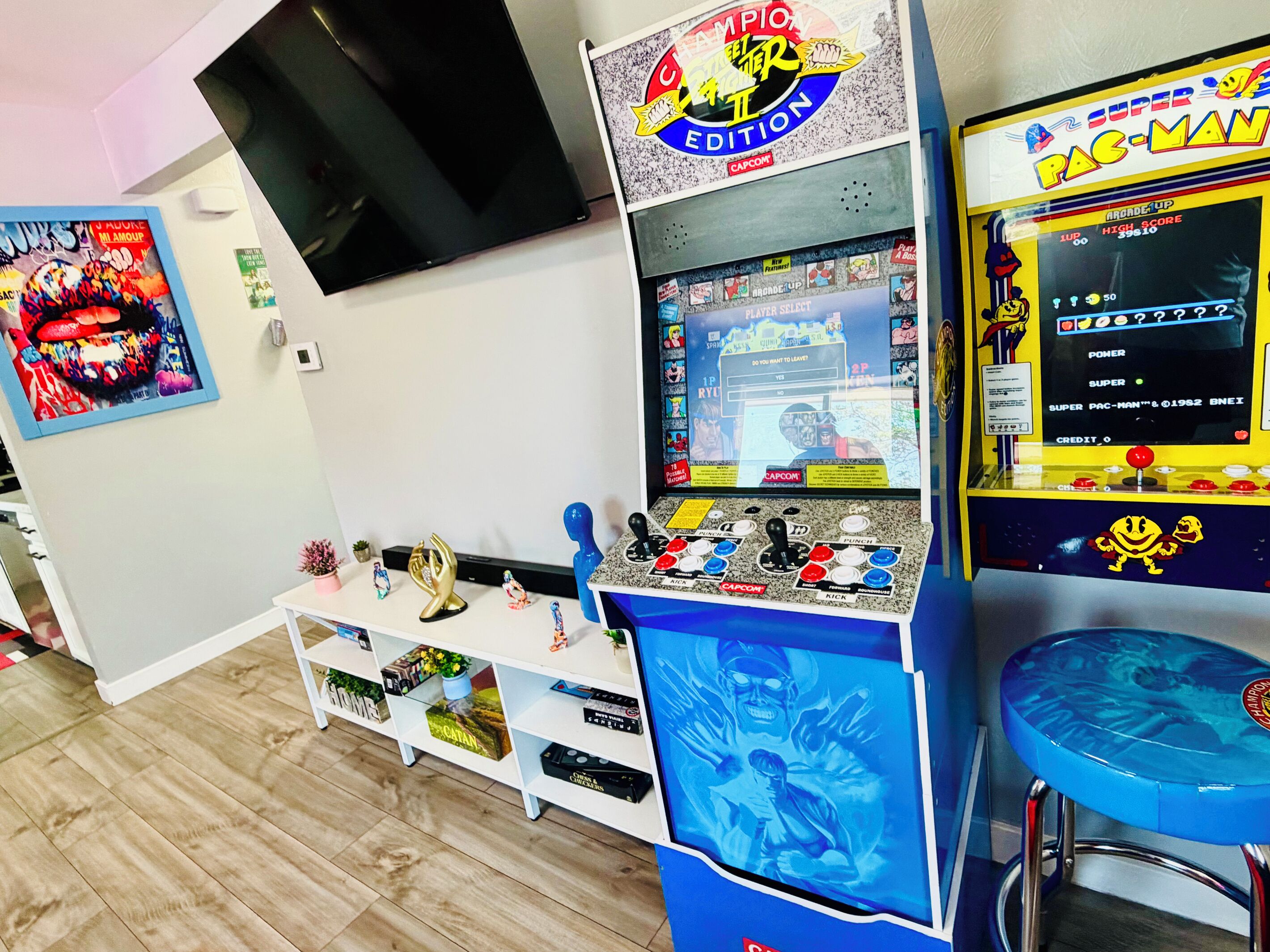 A room with arcade games, a television, and a shelf with various items.