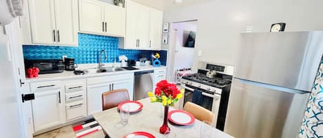 A modern kitchen with white cabinets, a blue backsplash, and stainless steel appliances.