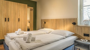 Une chambre d’hôtel avec deux lits, une armoire en bois et une fenêtre donnant sur un paysage agréable.