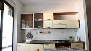 A kitchen with cabinets, a stove, a sink, and a table with a tablecloth. - M328 - Marcelli, two-room apartment with sea view (Marcelli)