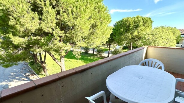 A balcony with a table and chairs, overlooking a grassy area with trees. - M328 - Marcelli, two-room apartment with sea view (Marcelli)