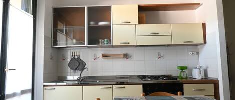 A kitchen with cabinets, a stove, a sink, and a table with a tablecloth.