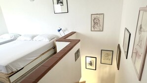 A bedroom with a bed, a staircase, and framed artwork on the walls. - M328 - Marcelli, two-room apartment with sea view (Marcelli)