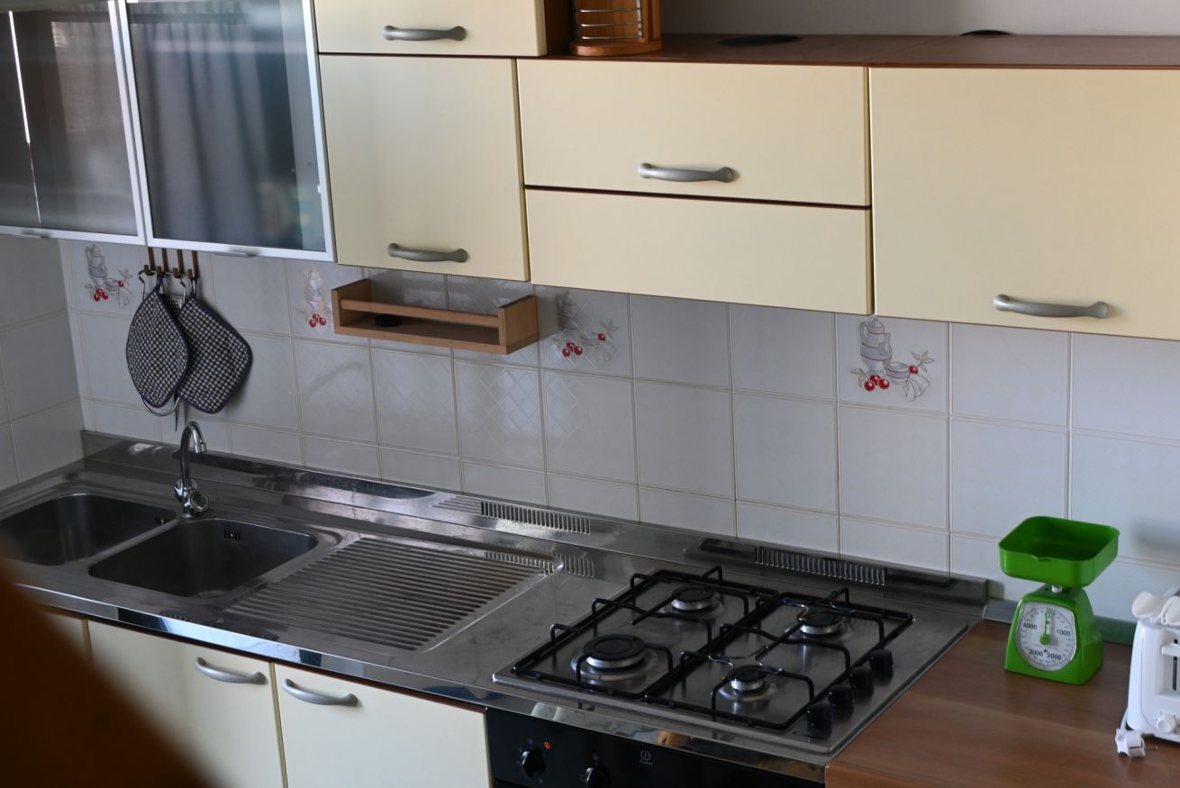 A kitchen with a gas stove, double sink, and a green scale on the countertop.