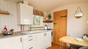 A compact kitchen with white cabinets, a wooden countertop, and a dining area with a table and chairs.