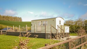 A small, single-story mobile home with a porch and a fenced area.