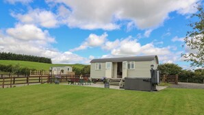 A single-story mobile home with a porch and a small garden area. - Hillside View Shepherds Hut Sleeps 2 (Rhayader)