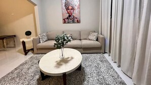 A living room with a beige sofa, a round coffee table with a vase, and a painting on the wall. - APARTMENT 1 · Stunning 3-Br Apt in Condado (San Juan)