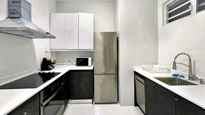 A compact kitchen with white cabinets, a stainless steel refrigerator, a microwave, and a sink with a faucet. - APARTMENT 1 · Stunning 3-Br Apt in Condado (San Juan)