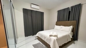 A bedroom with a bed, a window with curtains, an air conditioning unit, and a small rug. - APARTMENT 1 · Stunning 3-Br Apt in Condado (San Juan)