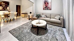 A modern living room with a round coffee table, a sofa, and a dining area with chairs. - APARTMENT 1 · Stunning 3-Br Apt in Condado (San Juan)