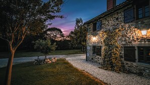 A stone building with a gravel path and a tree.