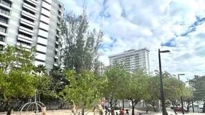 Un parque público con juegos infantiles, árboles y un camino pavimentado.