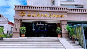 L’entrée de l’hôtel international Yuxi, avec une enseigne bien visible au-dessus des portes et un escalier menant à l’intérieur.