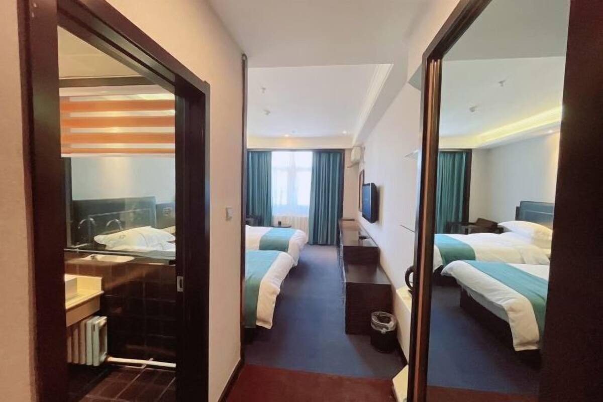 Ein Hotelzimmer mit zwei Betten, einem Badezimmer und einem großen Spiegel.