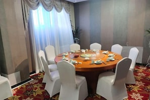 Une salle de conférence avec une table ronde, des chaises blanches et un sol recouvert d’une moquette rouge.