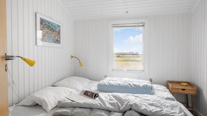 Un dormitorio con cama, dos lámparas de noche, una ventana con vistas al exterior y una mesita de noche de madera.