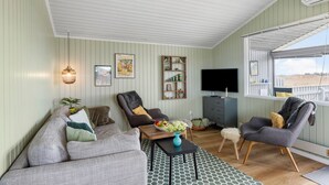 Una sala de estar con sofá, dos sillones, una mesa de centro, televisor y ventana con vistas.