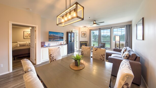 Ein modernes Wohnzimmer mit Esstisch, Sofas und Deckenventilator.