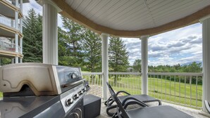 Un patio coperto con barbecue, poltrona relax e vista su un campo da golf.