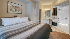 A bedroom with a bed, a bathroom with a shower, and a framed picture on the wall. - Mountain Rook 2 king bedroom, sleeps 6: Unit 1002 (Fairmont Hot Springs)