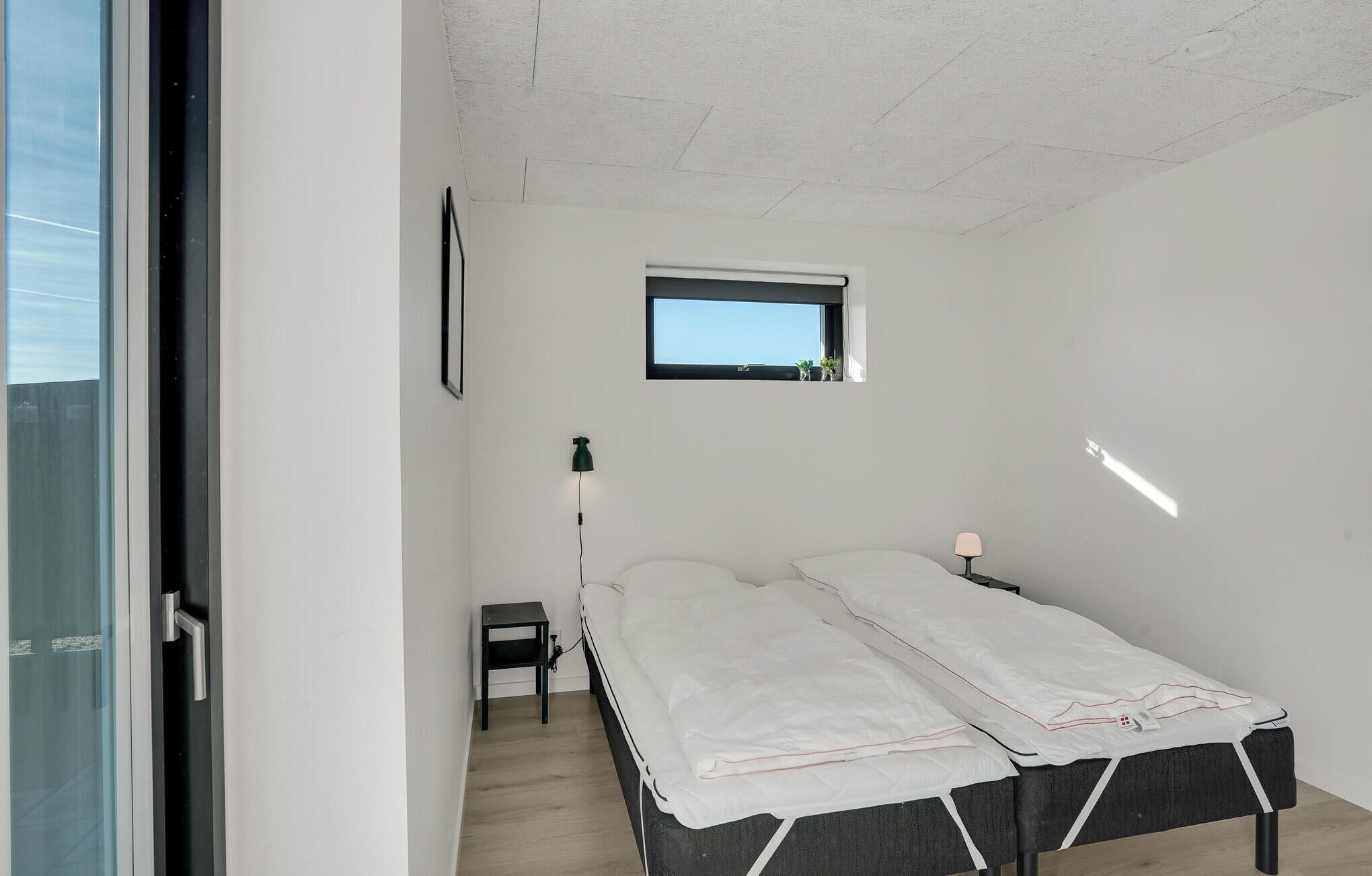 Un dormitorio con cama, una mesita, una lámpara y ventana.