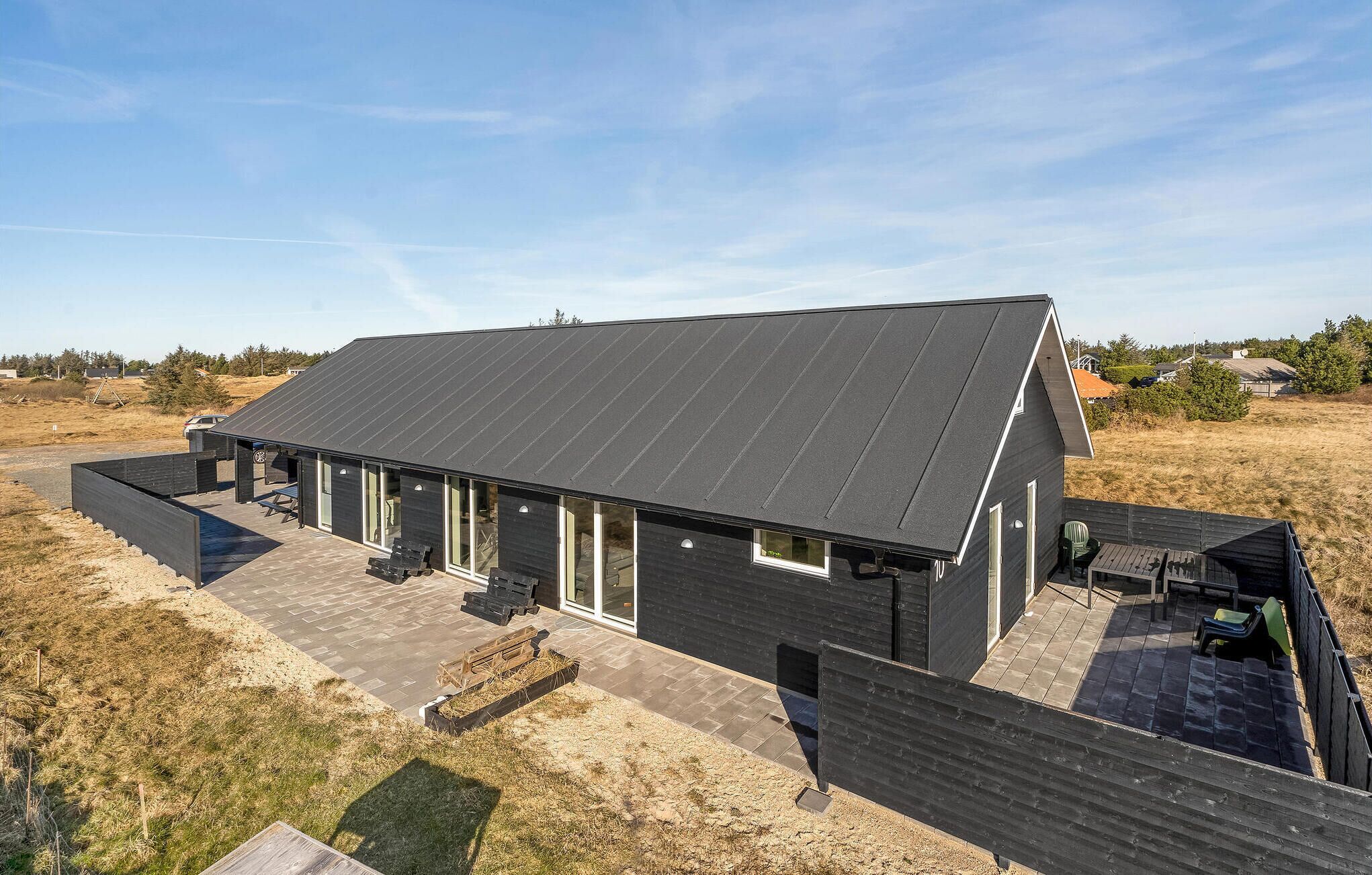 A modern house with a sloped roof, large windows, and a covered patio area.