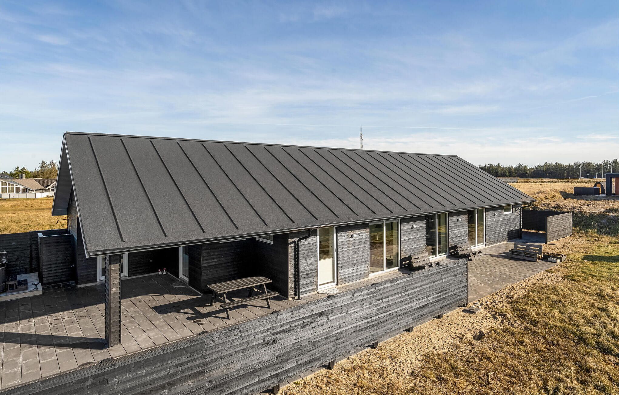 A modern building with a sloped roof, large windows, and a wooden deck area.