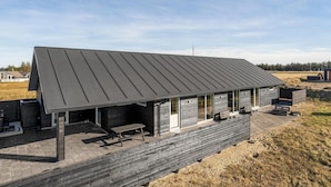 A modern building with a sloped roof, large windows, and a wooden deck area.