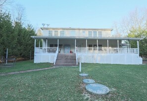 A two-story building with a covered porch and a set of stairs leading to the entrance.