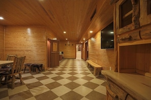 A wooden interior with a checkered floor, wooden benches, and a long hallway.