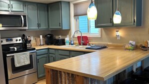 A modern kitchen with a central island, stainless steel appliances, and pendant lighting.