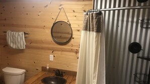 Un baño con paneles de madera, un lavamanos, un espejo y un inodoro.