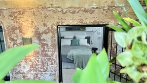 A rustic room with a worn wall, a bed with a green blanket, and a small table. - Live like a local in the heart of Surry Hills (Surry Hills)