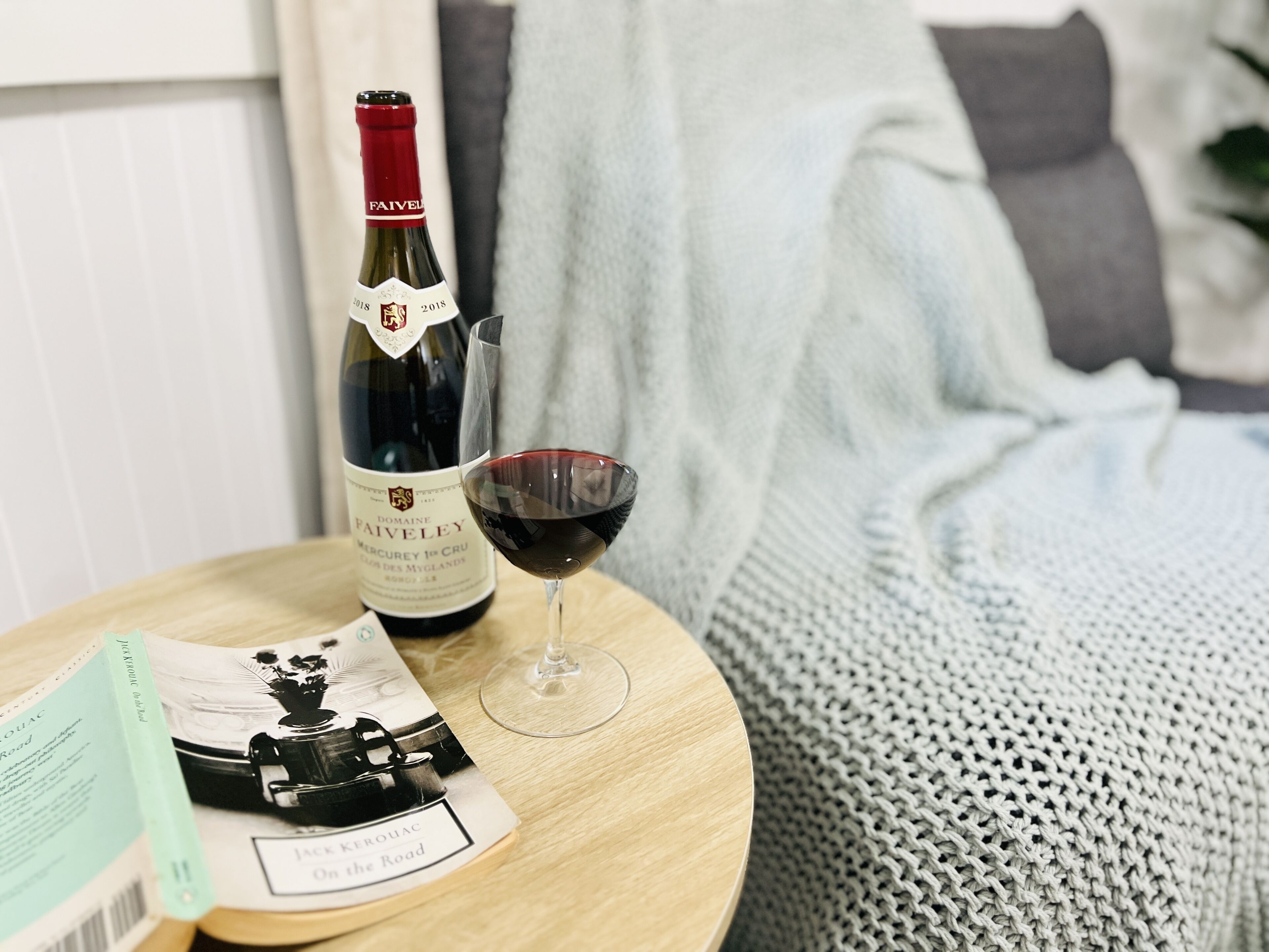 Une bouteille de vin du domaine Faiveley et un verre de vin rouge sur une table en bois.