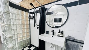 A bathroom with a checkered floor, a glass shower enclosure, a white sink, a mirror, and a towel rack. - Live like a local in the heart of Surry Hills (Surry Hills)