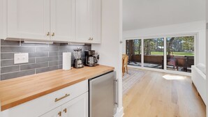 Een moderne keuken met witte kastjes, een houten aanrecht en een koffiezetapparaat.